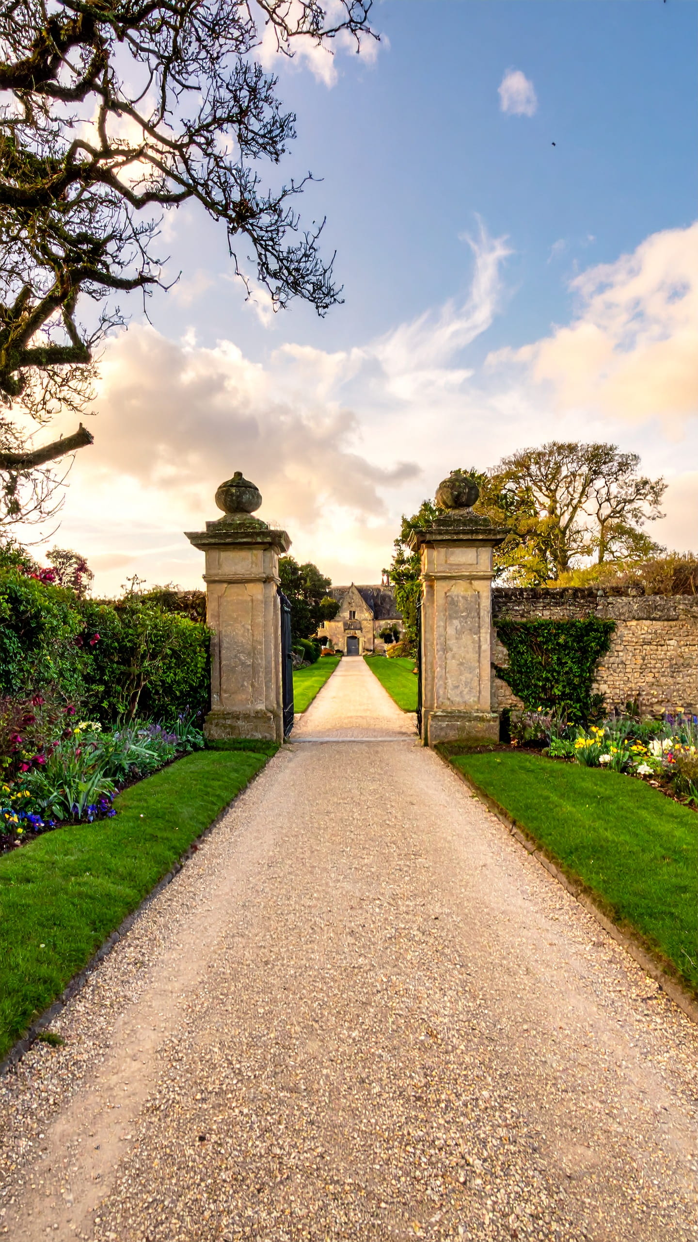 Cotswold garden gate opening onto a manor house walk in spring